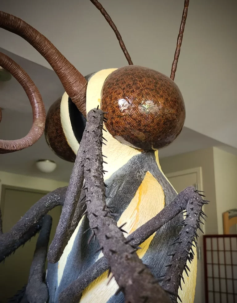 Enormous suspended caterpillar sculpture part 2displaying characteristic warning coloration stripes and segmented body with extending prolegs. Museum installation transforms tiny larval form into monumental presence with organic textures and dynamic spatial composition.