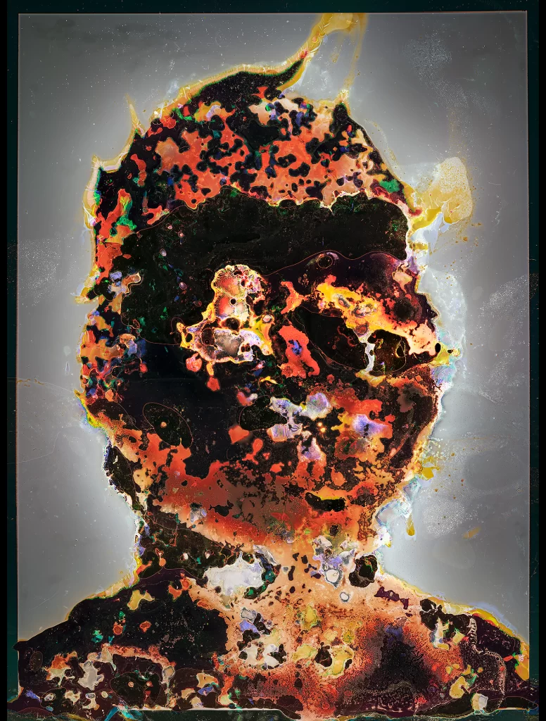 Experimental self-portrait produced via subterranean photographic processing on film stock showing frontal figure with luminous aureate corona. Composition exhibits vibrant organic transformation including orange chemical alterations, verdant biological growth, ebony material consumption, and celestial radiance effects from earthbound decomposition creating transcendent appearance.