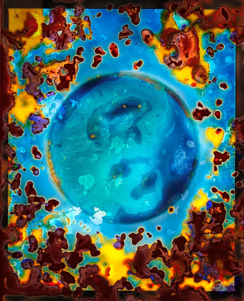 Alternative photographic process artwork showing dominant azure circle amid fiery golden eruptions. Underground film burial method produces celestial composition with planetary sphere surrounded by solar-colored chemical staining and decomposed matter patterns.